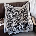 Detail of black and white rose pattern scarf with polka dots on a leather bench - Black