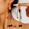 Detailed close-up of a model wearing Halloween skull tassel earrings with colorful beads - Orange