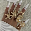 Set di 6 anelli dorati con stelle marine, conchiglie e perle indossati sulla mano - Set da 6 Pezzi Stella Marina Conchiglia e Perla Artificiale (30371-ring-G)