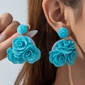 Three turquoise floral cluster earrings in woven fabric shown on a model - Teal