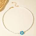 Dettaglio della collana di perline bianche con ciondolo a fiore di frangipane blu sfumato - Blu (29919-nek-blu)