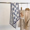 Detailed view of blue paisley silk scarf styled with a beige suit on a hanger - White