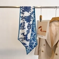 Detailed view of long silk neck scarf with paisley patterns draped on a metal rack - Blue