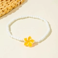 Macro detail of white beaded anklet with a bright yellow plumeria flower resin pendant - Orange Frangipani Style