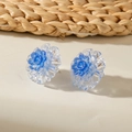 Detail of floral earrings featuring layered blue glitter petals and resin texture - Blue