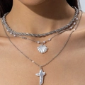 Gros plan du collier triple rang argenté avec pendentifs coquillage et croix en perle - Collier Coquille Argent 3 Couches (31379-nek-S-EP)