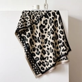 Detail of leopard print scarf with dotted borders and fringe trim on a display stand - Beige-Black