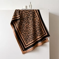 Dettaglio della sciarpa leopardata con bordi neri cuciti e fini frange corte - 66*188cm / Caffè Nero