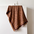 Dettaglio della frangia sulla sciarpa leopardata drappeggiata su blocchi bianchi minimalisti - 66*188cm / Caramello