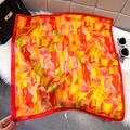Silk-like square scarf with red orange floral print on a plush white rug background - Red (Abstract Flame Floral)