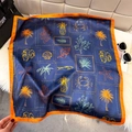 Navy blue silk square scarf with orange borders and tropical ocean print displayed on a bag - Dark Blue (Island Vacation)