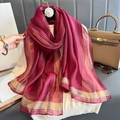 Pañuelo de seda rojo oscuro con rayas doradas sobre un top de punto blanco - Granate