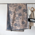 Dettaglio di uno scialle beige effetto cashmere con fiori blu e bordi con nappine - Blu