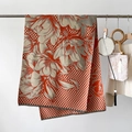 Detail of plaid scarf featuring orange floral patterns and gray checkered knit texture - Orange