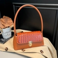 Caramel brown crocodile embossed baguette handbag with gold clasp on aesthetic background - Brown