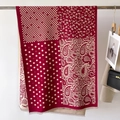Dettaglio di sciarpa bordeaux con motivi paisley e pois con bordi a frange morbide - Rosso