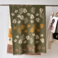 Dettaglio di sciarpa verde con stampa ginkgo e frange appesa a una parete - 66*186cm / Verde