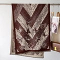Detail of soft brown and beige butterfly pattern scarf with fringe and knit texture - Caramel color