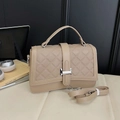 Quilted beige crossbody handbag with silver H-buckle and adjustable strap on a sofa - Khaki