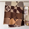 Détail d'une écharpe à carreaux tons terre avec motif pied-de-poule et franges - Café