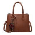 Brown litchi leather tote bag with dual handles and leopard bear charm on white background - Brown