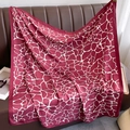 Dettaglio di un foulard in seta con stampa giraffa rosso scuro e texture satinata - Rosso