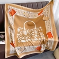 Detail of silk square scarf in camel with elegant handbag patterns on a leather bench - Khaki