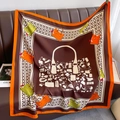 Detail view of square silk scarf featuring handbag and houndstooth patterns on leather sofa - Caramel color