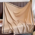 Close-up of beige polka dot silk scarf draped on a leather sofa with elegant texture - Khaki