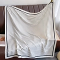 Polka dot silk scarf draped over a leather sofa showing draped texture and pattern - White