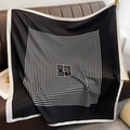 Dettaglio di un grande foulard in seta con linee geometriche su un divano in pelle - 90*90cm / Nero