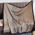 Dettaglio di un foulard in seta con motivo pied de poule e catene su divano in pelle - Taglia unica / Cachi scuro