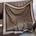 Detailed view of luxury vintage monogram silk scarf draped on a leather sofa - 90*90cm / Coffee