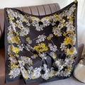 Vue détaillée d'un foulard en soie à imprimé floral posé sur un canapé en cuir marron - Grandes Fleurs Jaunes (XW-47)