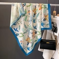 Elegant floral silk scarf with orange and blue prints draped next to a luxury handbag - 90x90cm / White