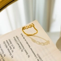 Close-up of golden hollow heart chain ring placed on vintage book pages for artistic detail - US 6 / Hollow Linked Hearts