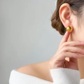 Polished gold hollow sphere earrings worn by a model in a minimalist stylish setting - Hollow Round Ball