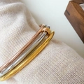 Close-up of three-tone titanium steel bangles on soft beige knit fabric textures - Three-Tone Interlocking Rings Bangle