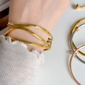 Close-up of three-layer wave stacked bangle in polished gold finish on wrist - Triple Wavy Line Cuff Bangle