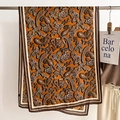 Detailopname van retro paisley sjaal in oranje met zijdeachtige textuur en gestreepte rand - Gembergeel