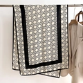 Detail of a thin beige scarf with geometric pattern and black borders hanging by a blazer - Black Border Style (FSM-16)
