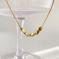 Collar minimalista de cadena dorada con cinco cuentas retorcidas pulidas sobre cristal - Dorado