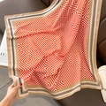 Gros plan d'un châle à rayures orange et blanc sur un canapé en cuir avec des accessoires - Rose