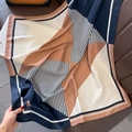 Dettaglio di un foulard in seta con patchwork geometrico e strisce su pelle - Beige