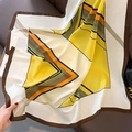Gros plan du foulard en soie à rayures géométriques avec motif contrasté orange et noir - Jaune