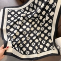 Detail of silk-feel scarf with camellia and polka dot pattern next to fashion magazine - Black