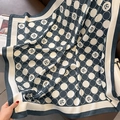 Detail of camellia pattern on a navy blue polka dot scarf draped on a leather sofa - Navy Blue