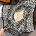 Détail d'une écharpe à motifs géométriques noir et blanc sur un canapé en cuir - Bordure Noire (HSM-11)
