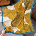 Dettaglio di sciarpa con piume gialle e nere su divano in pelle con accessori chic - Bordo Blu