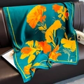 Dettaglio di sciarpa in seta con fiori arancioni su divano in pelle che mostra il drappeggio - 90*180cm / Blu Lago